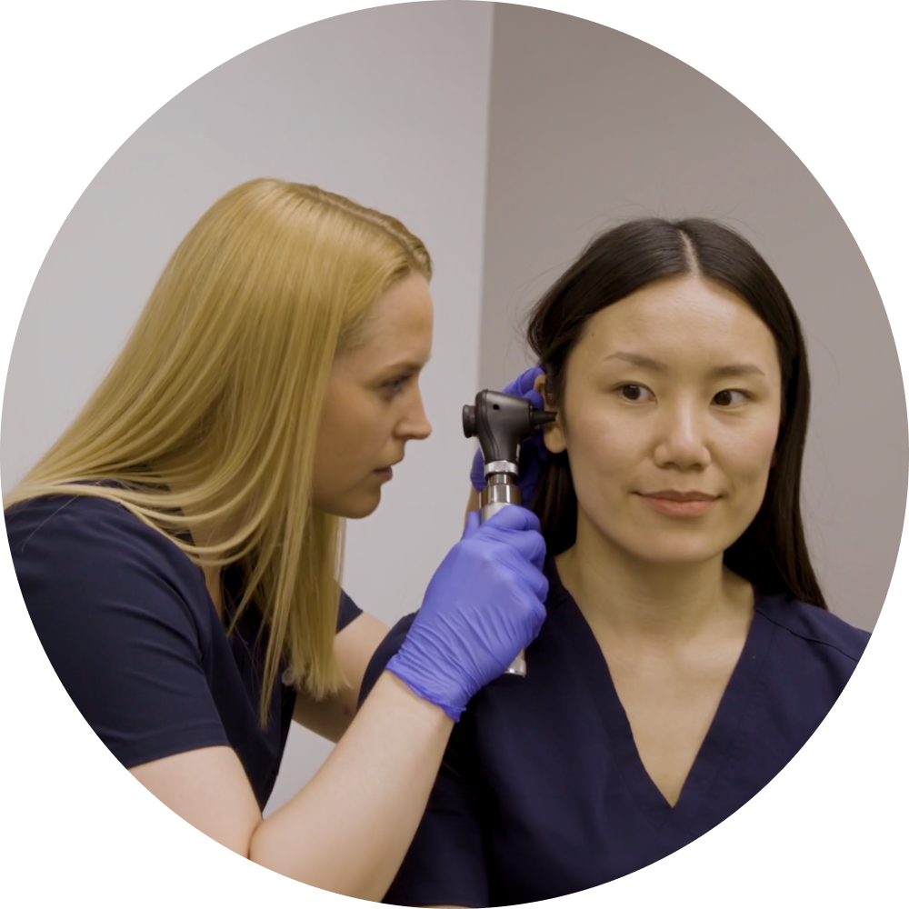 student using an otoscope on other student.