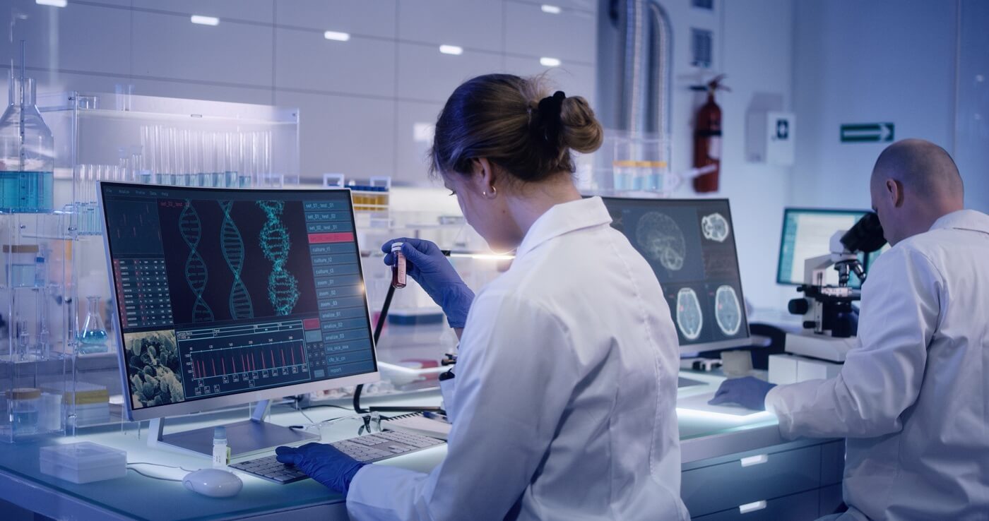 Two scientists examine models of DNA on computer screens.