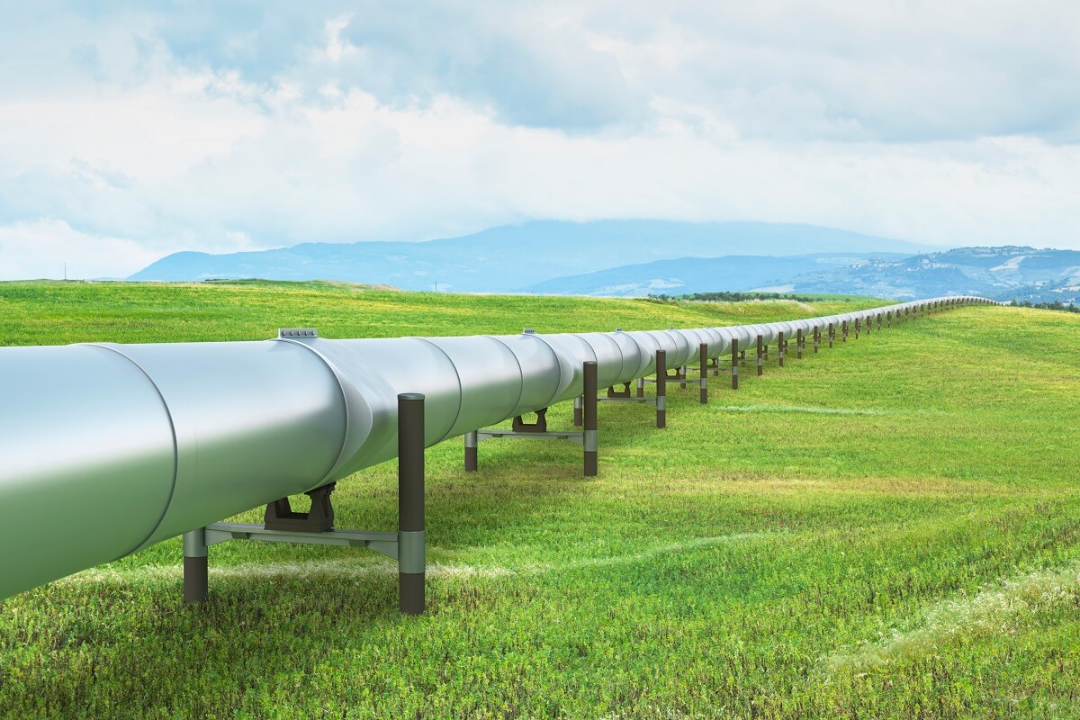 A silver-colored pipe transporting liquid over a field.