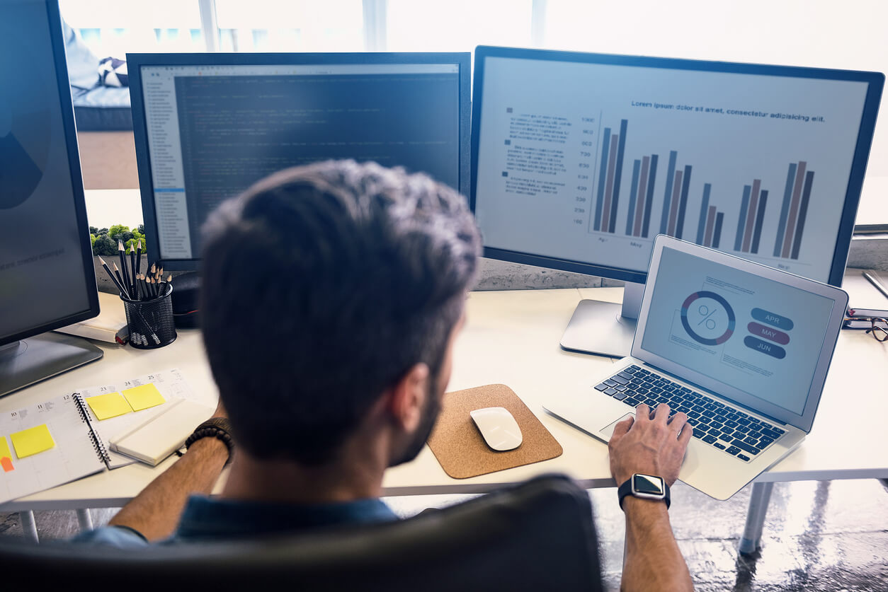 a man looking at data on several monitors.