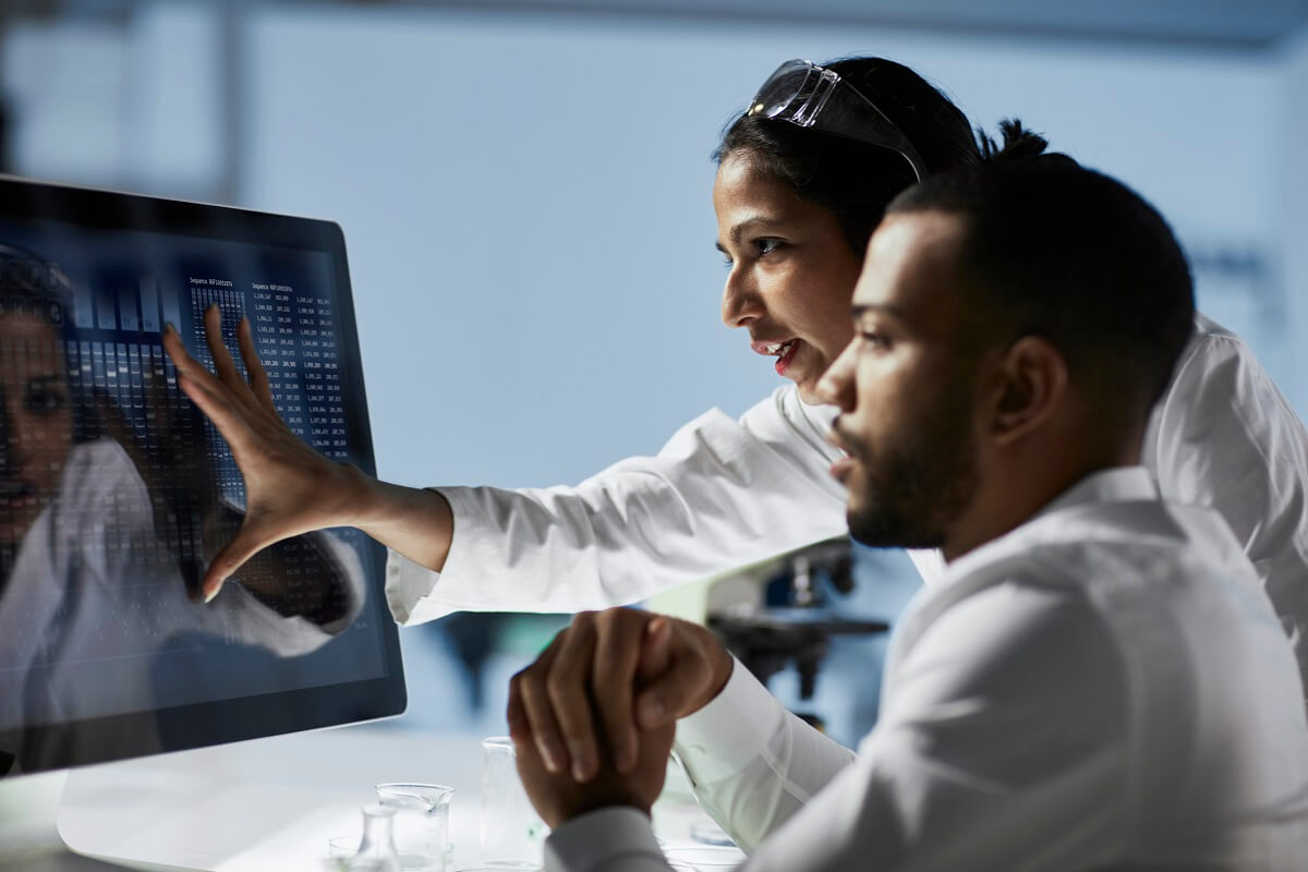 Two physicians in lab coats reviewing healthcare data on a computer screen
